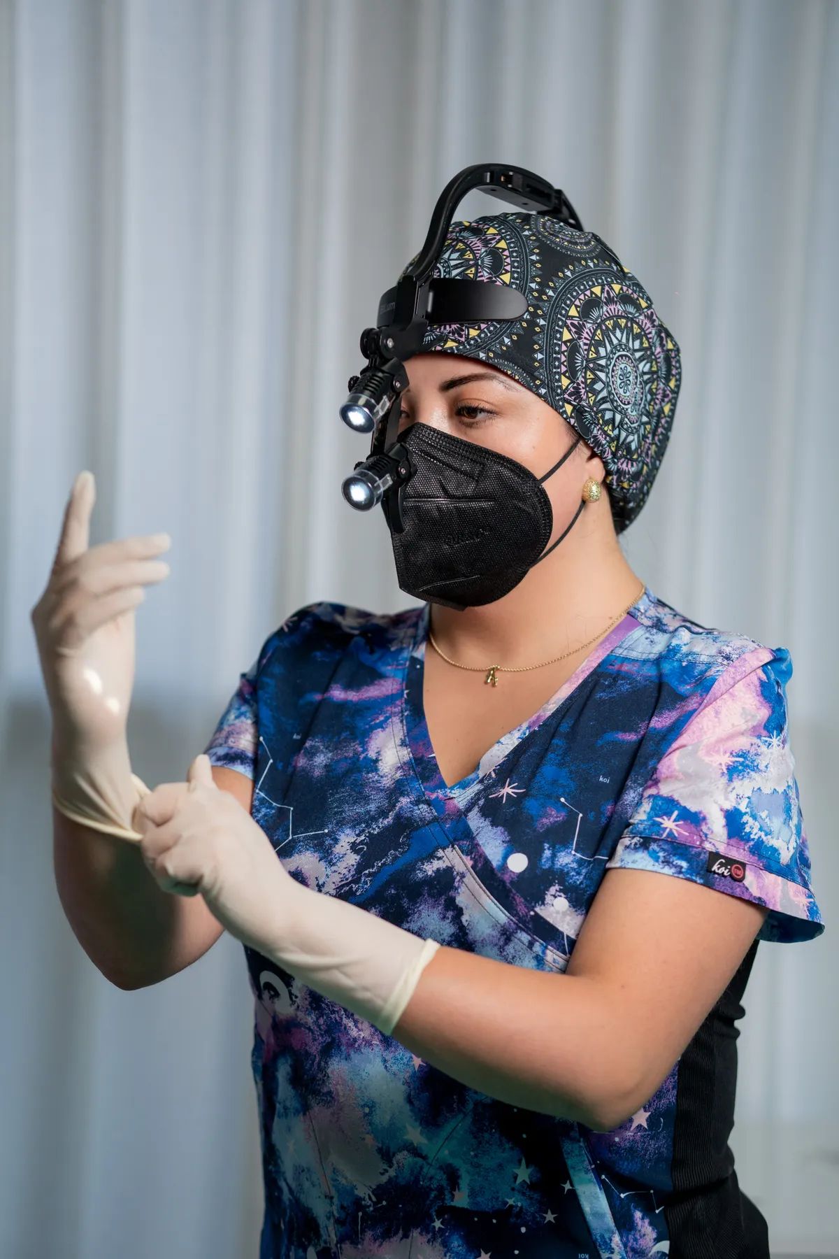 Dra. Alytsa Garcia con lupas quirúrgicas iluminadas colocándose los guantes